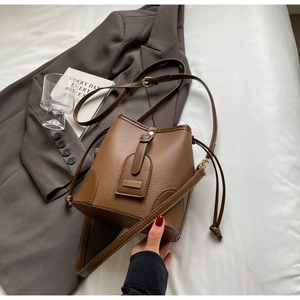 Detail of dark brown lychee grain leather bucket bag with gold hardware and drawstring