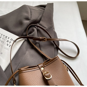 Detail of vintage brown bucket bag showing lychee grain leather and gold metal buckle
