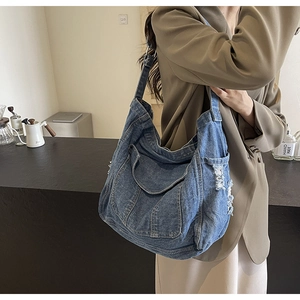 Detail of dark blue denim hobo bag with vintage distressed edges and side pocket