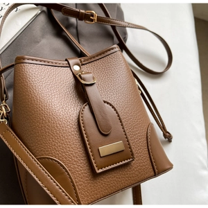 Detail of brown litchi pattern leather bucket bag with elegant gold metal hardware