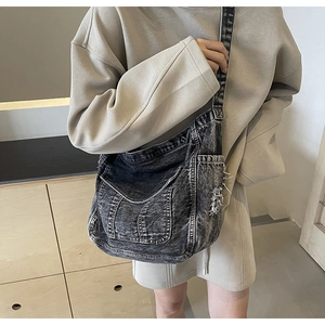 Detail of vintage washed denim crossbody bag featuring distressed frayed edges and side pocket