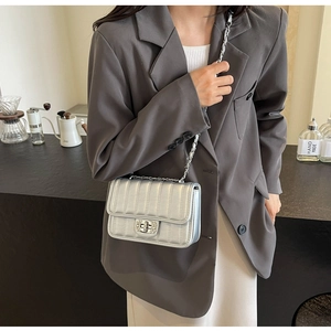 Detail of silver quilted crossbody bag with rhinestone buckle and metal chain strap
