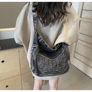 Detail of vintage washed black denim hobo bag with raw edge design and wide shoulder strap