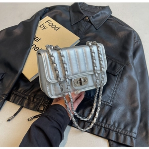 Detail of silver quilted chain bag with rhinestone lock and metallic leather strap