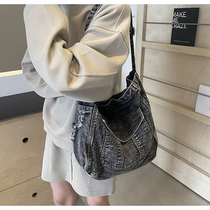 Close-up of a vintage black-grey denim hobo bag featuring frayed edges and a soft structure