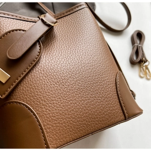 Detail view of brown lychee texture leather bucket bag with metallic buckle and strap