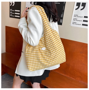 Detailed side view of a large yellow and white checkered canvas tote bag worn by a model