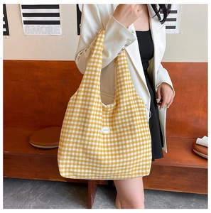 Detail shot of yellow checkered knit tote bag with integrated strap and 'good' patch
