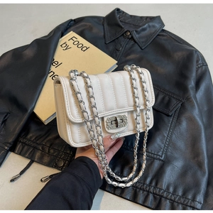 Detail of quilted beige crossbody bag with sparkling rhinestone lock and chain strap