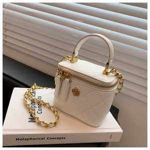 Primer plano del mini bolso cubo acolchado blanco con logo floral dorado y cadena