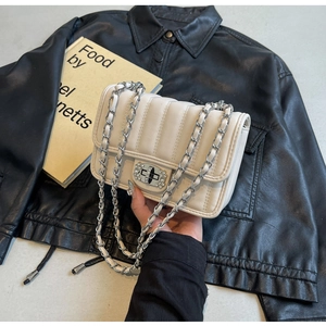Close-up of quilted cream crossbody bag with rhinestone lock and chain strap