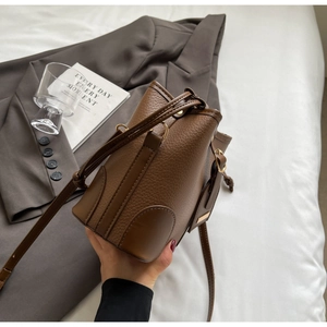 Detail of vintage brown pebble leather bucket bag with gold hardware and adjustable strap