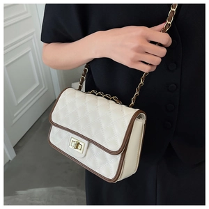 Dettaglio borsa trapuntata beige con bordi marroni e chiusura dorata sulla modella