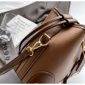 Detail of dark brown lychee leather handbag featuring golden metal hardware and drawstring