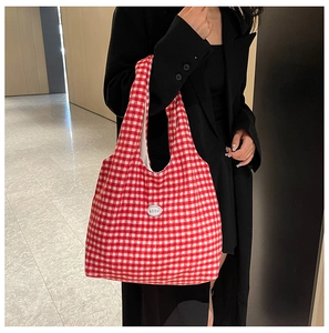 Detail of red and white gingham canvas tote bag with good patch on a black blazer