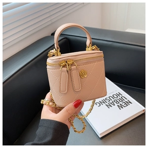 Detalle de mini bolso acolchado rosa claro con dije de camelia dorada y cadena de oro