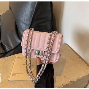 Detail of pink quilted shoulder bag featuring silver chain strap and rhinestone lock closure