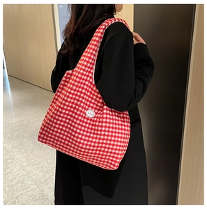Close-up of red and white checkered tote bag with good logo on a model shoulder