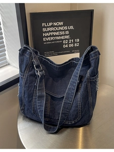 Large dark blue denim hobo tote bag with fringe details and adjustable shoulder strap