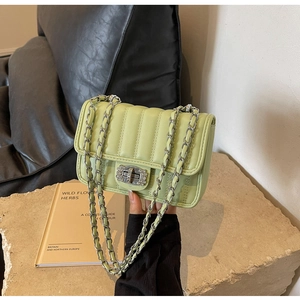 Close-up of light green quilted crossbody bag with silver chain and rhinestone lock