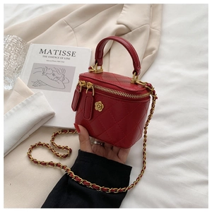 Detalle de mini bolso rojo acolchado con cierre de camelia dorada y correa en la mano