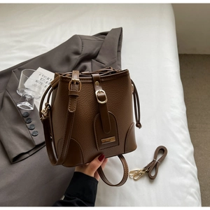 Detail of a brown lychee pattern bucket bag with drawstring closure and golden hardware