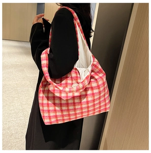 Close-up of a pink checkered canvas tote bag with a round button detail on wide strap