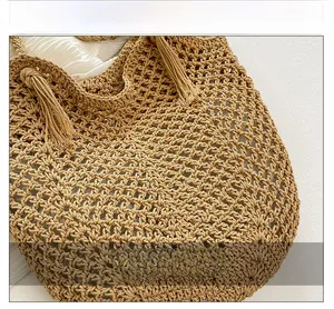 Detail of hand-woven straw tote bag with delicate crochet patterns and decorative tassels