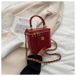 Primer plano del bolso mini acolchado rojo con hebilla de flor dorada y cadena