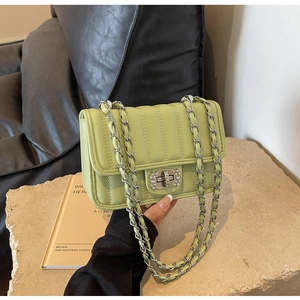Detail of avocado green quilted bag featuring rhinestone lock and silver chain strap