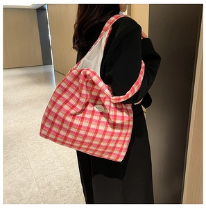 Pink and white plaid tote bag with 'good' patch shown worn over the shoulder by a model