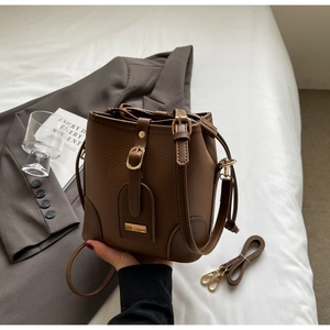 Detail of brown litchi pattern leather bucket bag with golden hardware and strap