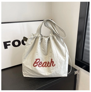 Detalle del bolso tote de nailon gris con estampado Beach rojo y diseño con cordón