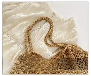 Close-up of hand-woven beige tote bag showing diamond mesh texture and fringe details