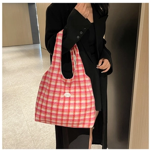 Detail of pink and white checkered knit tote bag showing the texture and good leather patch