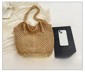 Detail of woven khaki tote bag with bohemian tassels and natural mesh texture
