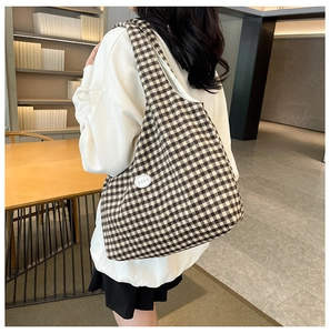 Detail of checkered canvas tote bag with a small leather good tag in a cozy room
