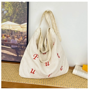 Dettaglio della borsa tote in velluto bianco con ricamo Future rosso su tavolo