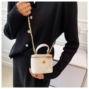 Detalle de bolso saco blanco acolchado con cadena dorada y emblema floral en modelo