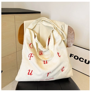 Dettaglio borsa tote in velluto a coste beige con ricamo Future rosso e trama fine