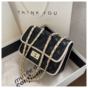 Dettaglio borsa in pelle nera trapuntata con bordo beige e chiusura girevole dorata