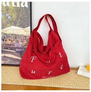 Dettaglio della borsa tote in velluto rosso con scritta Future su superficie gialla