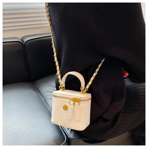 Detalle del mini bolso cubo blanco acolchado con cadena dorada y cremalleras de corazón