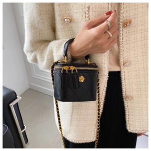 Detalle del mini bolso acolchado negro con cadena dorada y colgante de camelia
