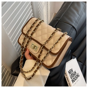 Dettaglio borsa a tracolla trapuntata beige con bordo marrone e chiusura a girello in metallo