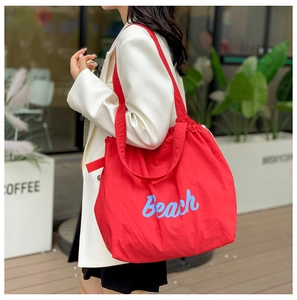 Primer plano del bolso tote rojo de nailon con texto Beach azul en estilo urbano