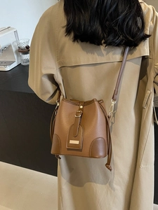 Chic brown lychee pattern leather bucket bag shown on a model in a minimalist setting