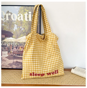 Macro shot of yellow plaid canvas tote bag fabric with red sleep well lettering