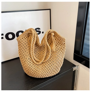 Détail d'un sac cabas en paille tressée avec pompon et texture en maille ajourée
