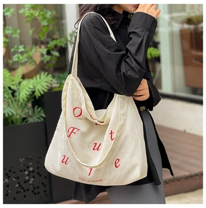 Dettaglio della borsa tote in velluto a coste bianco con ricamo Our Future rosso